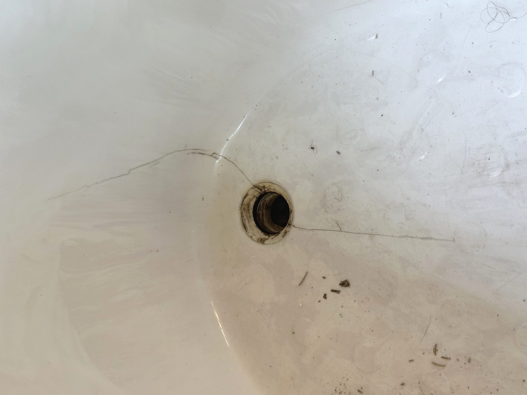 Cracked cultured marble tub near drain in Austin TX.