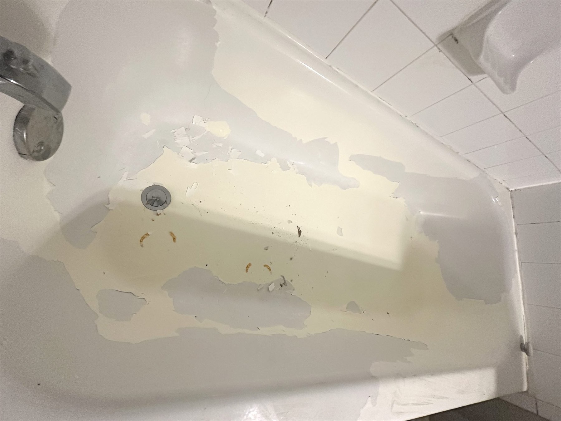 Peeling reglazed bathtub in Austin with failed bathtub refinishing coating.
